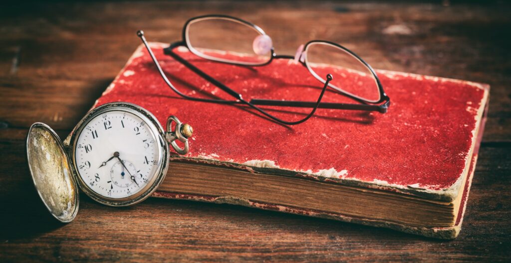 Pocket watch and eye glasses on an old book